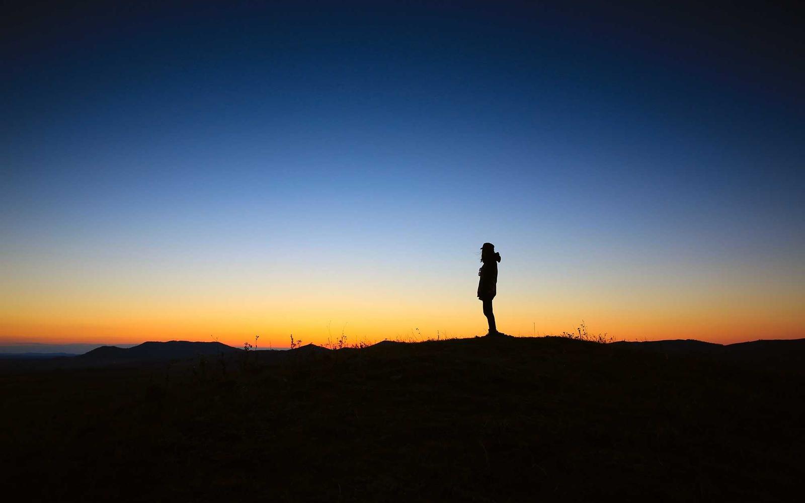 A dark empty mountain landscape beneath a star-filled sky
